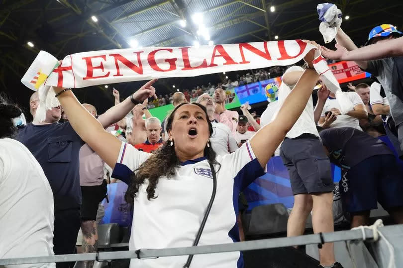 A fan holds an England scarf over their head in a stadium