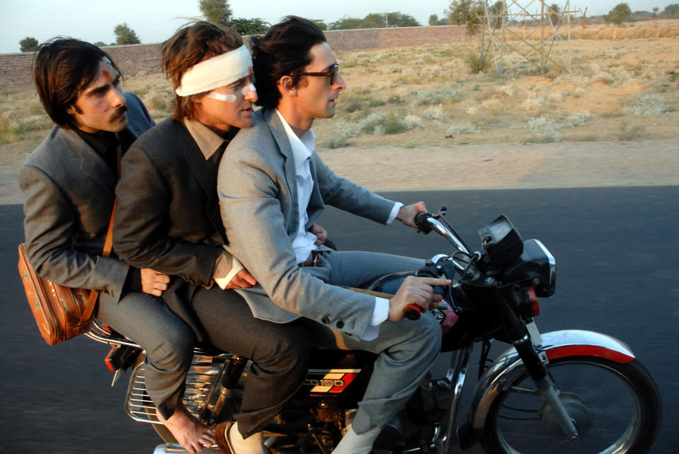 Jason Schwartzman, Owen Wilson, and Adrien Brody riding a motorcycle.