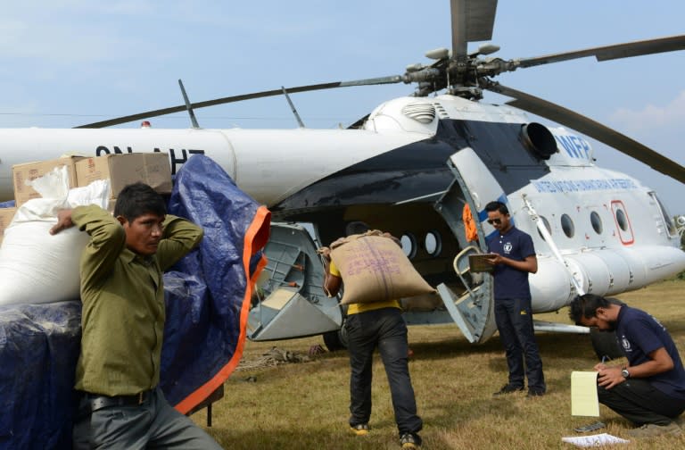 Nepalese villagers load relief materials onto a helicopter at Salyantaar in Dhading District