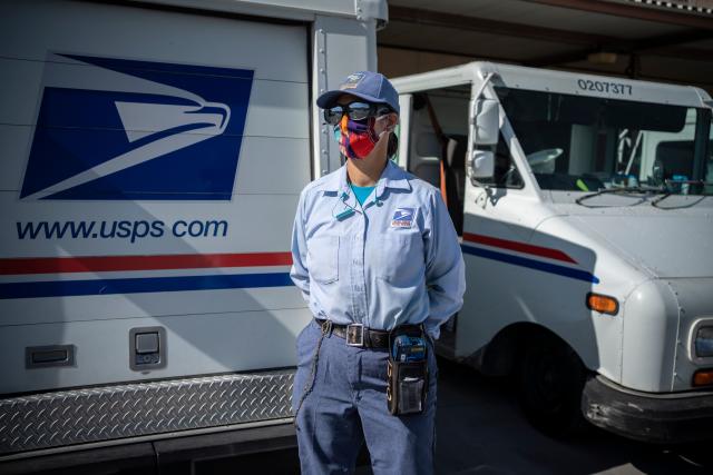 United States Postal Service mail carrier Lizette Portugal poses for a portrait in front of her truck before departing on her delivery route amid the coronavirus pandemic on April 30, 2020 in El Paso, Texas. - Everyday the United States Postal Service (USPS) employees work and deliver essential mail to customers. (Photo by Paul Ratje / AFP) (Photo by PAUL RATJE/AFP via Getty Images)