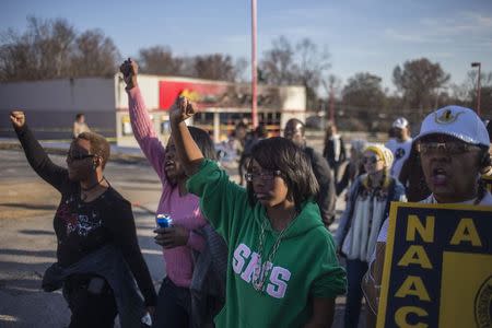 Supporters of the National Association for the Advancement of Colored People (NAACP), who were demanding justice for the killing of 18-year-old Michael Brown, march past a burned business in Ferguson, Missouri November 29, 2014. REUTERS/Adrees Latif