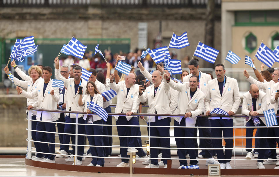 Athletes from Greece wave national flags on a boat as it sails along the Seine in Paris, France, during the opening ceremony of the 2024 Summer Olympics. / Credit: Michael Reaves / AP