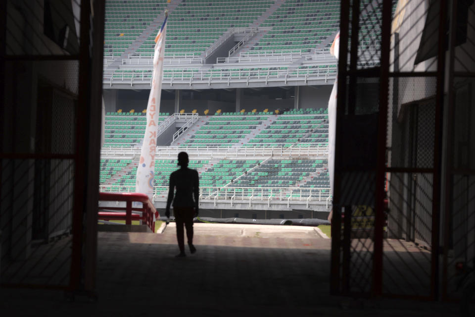 A worker is silhouetted against spectators seats at Gelora Bung Tomo Stadium, one of the venues prepared to host FIFA U-20 World Cup, in Surabaya, East Java, Indonesia, Thursday, March 30, 2023. Indonesia was stripped of hosting rights for the Under-20 World Cup on Wednesday only eight weeks before the start of the tournament amid political turmoil regarding Israel's participation. (AP Photo/Trisnadi)