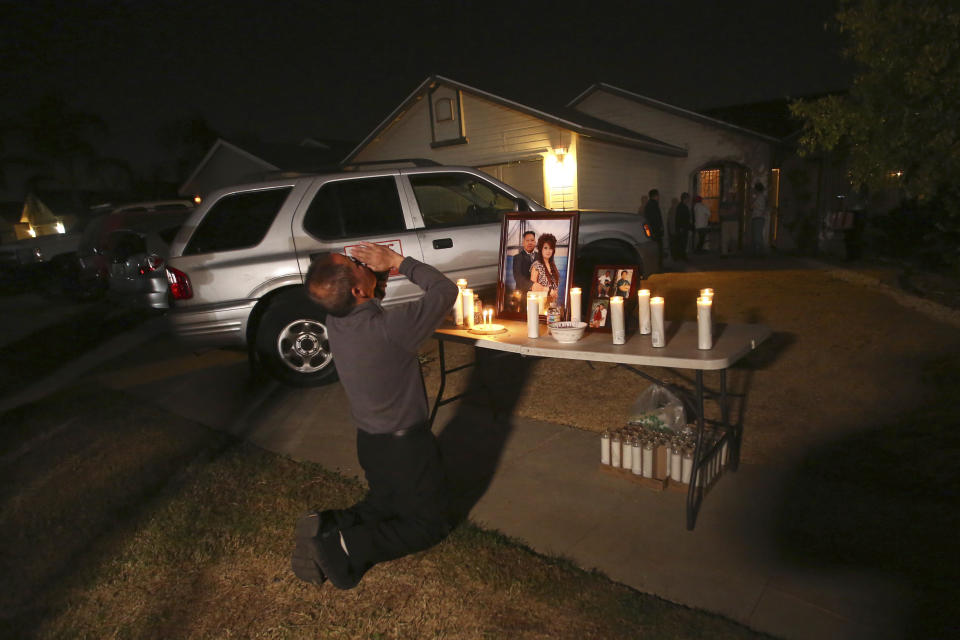 In this photo taken Monday, Nov. 18, 2019, Neej Xiong, uncle of shooting victim Kour Xiong, prays in front of a memorial during a candlelight vigil in Fresno, Calif. A close-knit Hmong community was in shock after gunmen burst into a California backyard gathering and shot 10 men, killing four. "We are right now just trying to figure out what to do, what are the next steps. How do we heal, how do we know what's going on," said Bobby Bliatout, a community leader. (Larry Valenzuela/The Fresno Bee via AP)