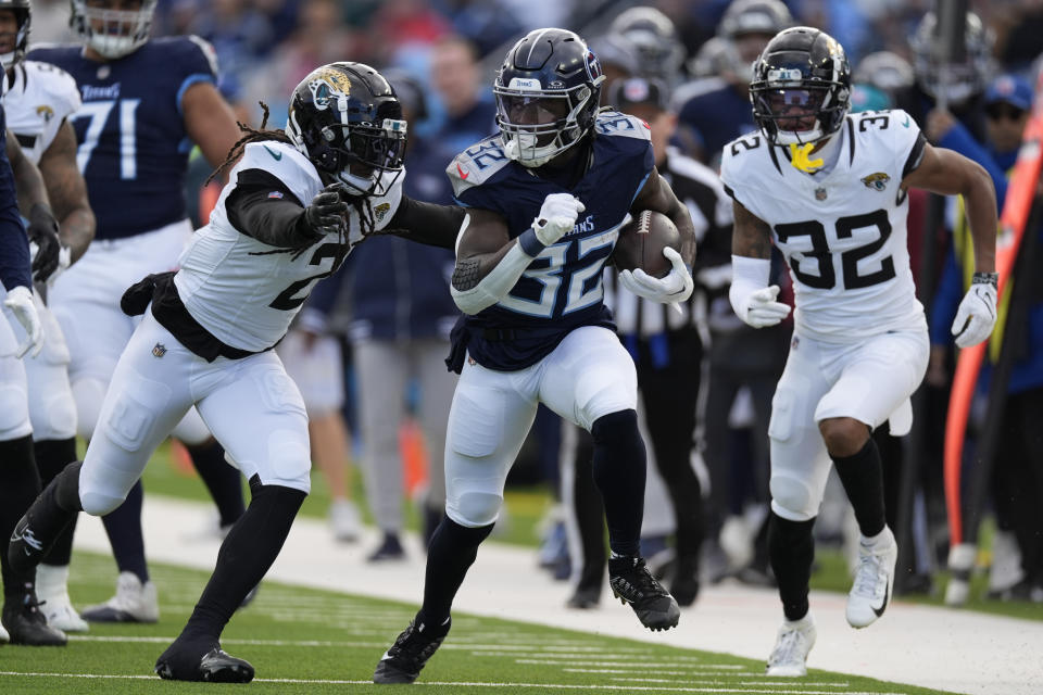 Tennessee Titans running back Tyjae Spears (32), center, runs for a first down against Jacksonville Jaguars safety Rayshawn Jenkins (2) and Tyson Campbell (32), right, during the first half of an NFL football game Sunday, Jan. 7, 2024, in Nashville, Tenn. (AP Photo/George Walker IV)