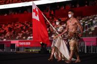 <p>Tonga's flag bearers Malia Paseka (L) and Pita Taufatofua lead the delegation during the Tokyo 2020 Olympic Games opening ceremony's parade of athletes. (Photo by HANNAH MCKAY/AFP via Getty Images)</p> 