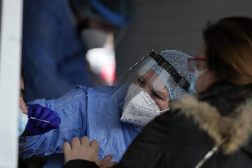 A member of the medical staff at the National Public Health Organisation (EODY) conducts a COVID-19 rapid test on a girl in Athens, Greece, Wednesday, Dec. 29, 2021. A government committee of medical experts hold an emergency meeting Wednesday to consider speeding up scheduled restrictions after the daily number of COVID-19 infections more than doubled in a day to set a new record. (AP Photo/Thanassis Stavrakis)