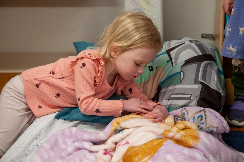 Charlee Hayes, a "Bluejays" student at the MetroWest YMCA Presechool, puts a doll to sleep during nap time, April 6, 2023.
