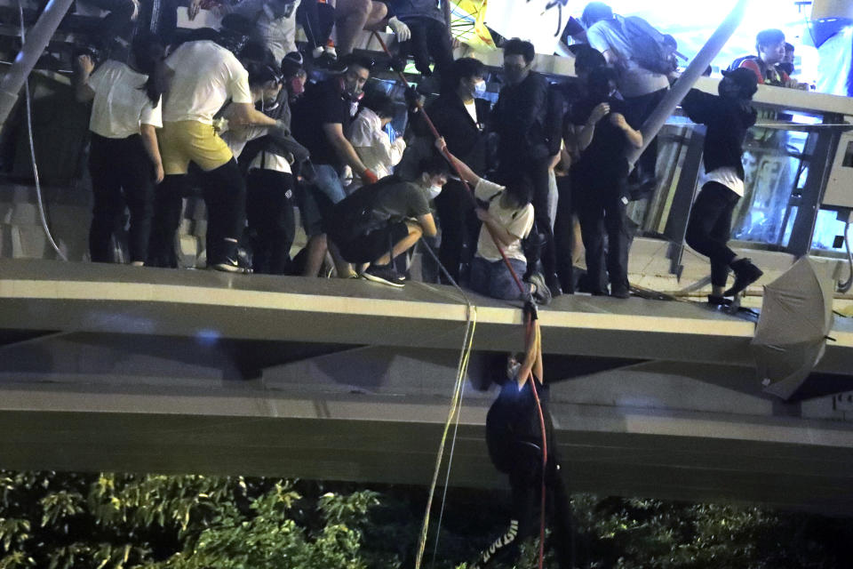 Protestors use a rope to lower themselves from a pedestrian bridge to waiting motorbikes in order to escape from Hong Kong Polytechnic University and the police in Hong Kong, Nov. 18, 2019. (Photo: Kin Cheung/AP)