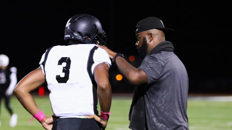 Roy Johnson, the football coach at Bishop Sycamore. talks with a player on the sideline.