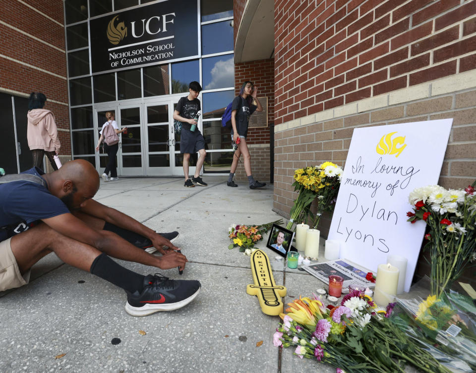 A person sits in front of the pop-up memorial for slain Spectrum News 13 journalist Dylan Lyons at the University of Central Florida Nicholson School of Communications in Orlando, Fla., Thursday, Feb. 23, 2023. Lyons, a graduate of UCF, was shot and killed while covering a homicide in Orlando on Wednesday. (Joe Burbank /Orlando Sentinel via AP)