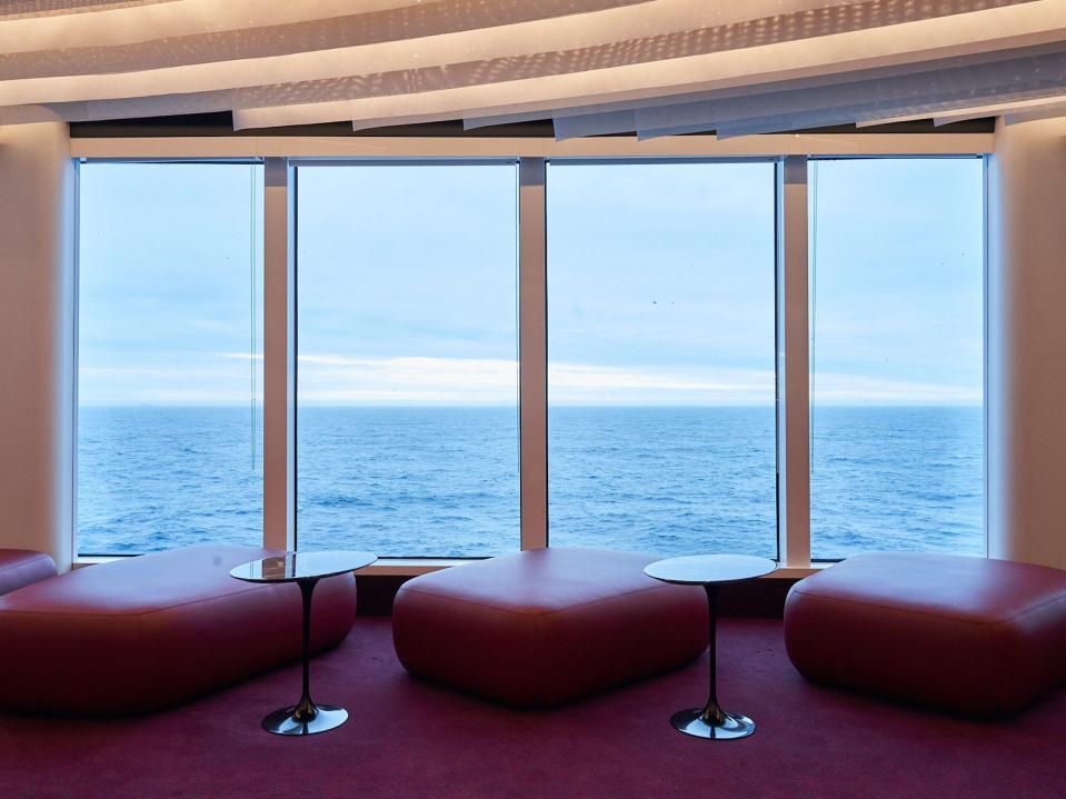 chairs and small tables in front of a windowed wall