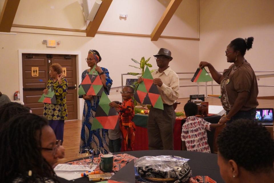 Audience members talk about what their "Unity Triangle" represents at the first day of Kwanzaa celebration held Tuesday at the Cotton Club Museum & Cultural Center.
(Credit: Photo by Voleer Thomas)