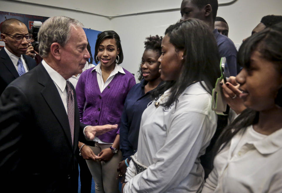 File-This photo from Tuesday, Dec. 3, 2013, shows New York's Mayor Michael Bloomberg, second from left, and Schools Chancellor Dennis Walcott, far left, meeting with senior students at the Bedford Academy High School in New York. Bloomberg campaigned on gaining control of the nation's largest public school system. left his mark by championing charter schools, expanding school choice, giving schools letter grades, and replacing scores of struggling institutions with clusters of small schools. (AP Photo/Bebeto Matthews, File)