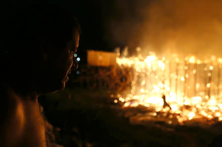 A man looks at houses on fire at Educando neighbourhood, a branch of the Rio Negro, a tributary to the Amazon river, in the city of Manaus, Brazil December 17, 2018. REUTERS/Bruno Kelly