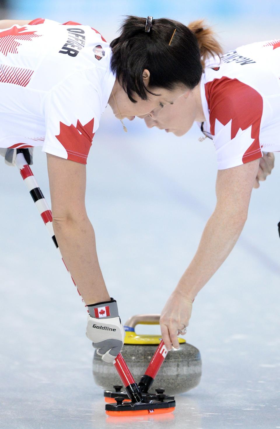 Canada's Jill Officer (L) and Dawn McEwen (R) brush the ice during the Women's Curling Round Robin Session 1 at the Ice Cube Curling Center during the Sochi Winter Olympics on February 10, 2014.