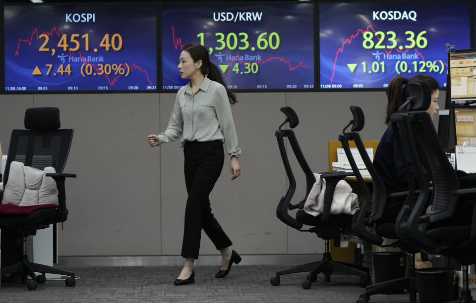 A currency trader passes by the screens showing the Korea Composite Stock Price Index (KOSPI), left, and the foreign exchange rate between U.S. dollar and South Korean won, center, at the foreign exchange dealing room of the KEB Hana Bank headquarters in Seoul, South Korea, Wednesday, Nov. 8, 2023. Asian shares were mixed in muted trading on Wednesday as attention focused on prospects for improved China-U.S. relations from meetings next week on the sidelines of a Pacific Rim summit. (AP Photo/Ahn Young-joon)