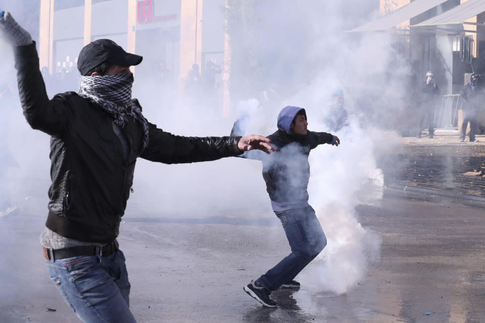 Anti-government demonstrators throw back canisters of tear gas to police during a protest against a parliament session in downtown Beirut, Lebanon, Tuesday, Feb. 11, 2020. (AP Photo/Bilal Hussein)
