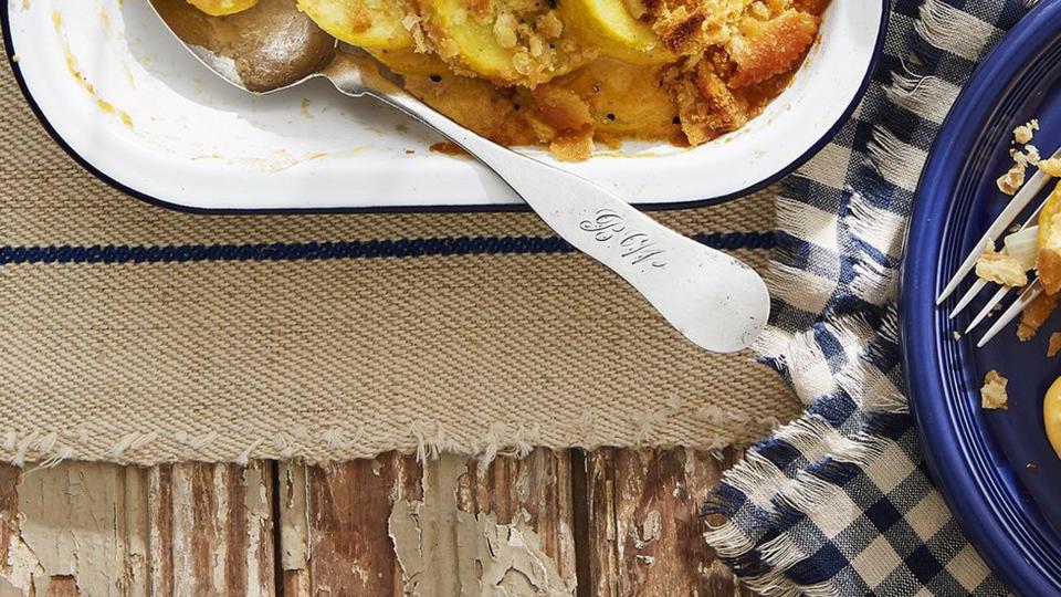 squash casserole in a white rectangle baking dish with a serving spoon