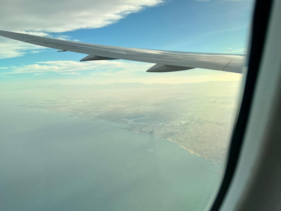 A view of the Dubai coast line as seen from the window of a Boeing 787 Dreamliner with the wing visible.