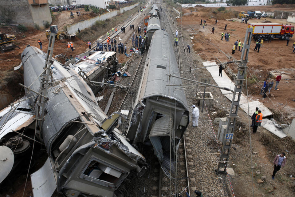 People gather after train derailed Tuesday Oct.16, 2018 near Sidi Bouknadel, Morocco. A shuttle train linking the Moroccan capital Rabat to a town further north on the Atlantic coast derailed Tuesday, killing several people and injuring dozens, Moroccan authorities and the state news agency said. (AP Photo/Abdeljalil Bounhar)