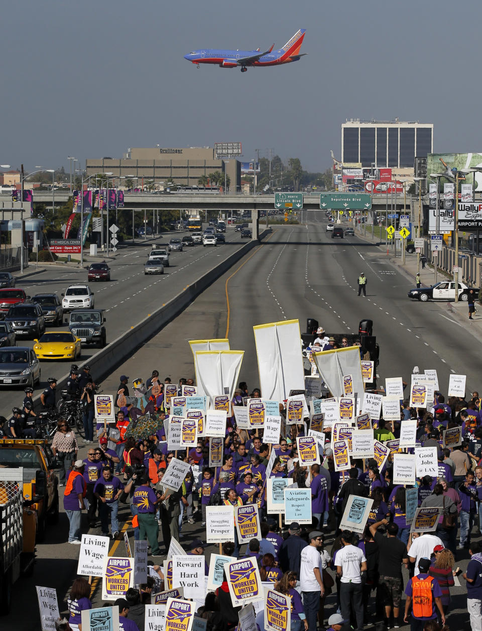 Union workers at Los Angeles International Airport march along the street near the airport in Los Angeles, Wednesday, Nov. 21, 2012. Hundreds of union members marched Wednesday near the entrance to Los Angeles International Airport, where Thanksgiving travelers were warned to arrive early in case of traffic snarls. (AP Photo/Jae C. Hong)