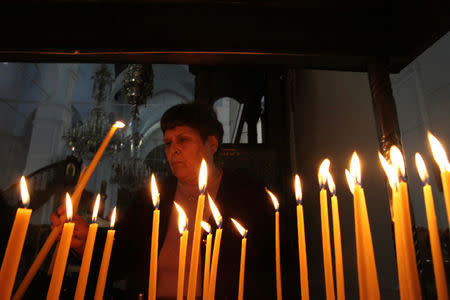 A woman lits candles inside the Orthodox Faneromeni church at the old town of Nicosia, Cyprus January 18, 2017. REUTERS/Yiannis Kourtoglou