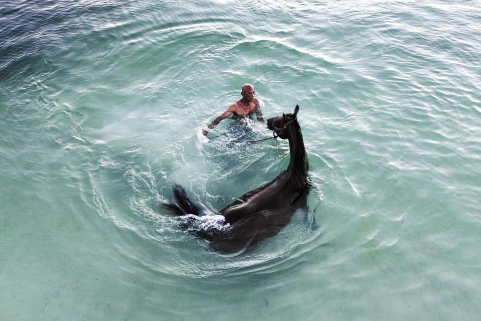 Denis Hooker trains his race horse named Pereque in the sea near the shore of San Andres Island in Colombia, on Nov. 11, 2022. (AP Photo/Ivan Valencia)