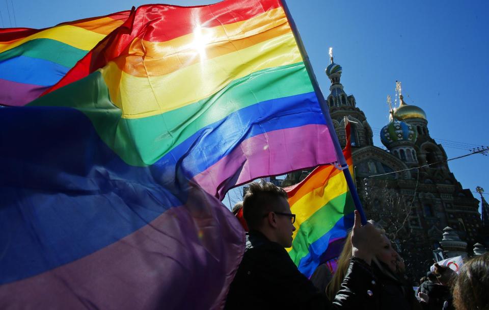 FILE - In this Wednesday, May 1, 2013, file photo, gay rights activists carry rainbow flags as they march during a May Day rally in St. Petersburg, Russia. When the Sochi Winter Olympics begin on Friday, Feb. 7, 2014 many will be watching to see whether Russia will enforce its law banning gay “propaganda” among minors if athletes, fans or activists wave rainbow flags or speak out in protest. The message so far has been confusing. (AP Photo/Dmitry Lovetsky, File)