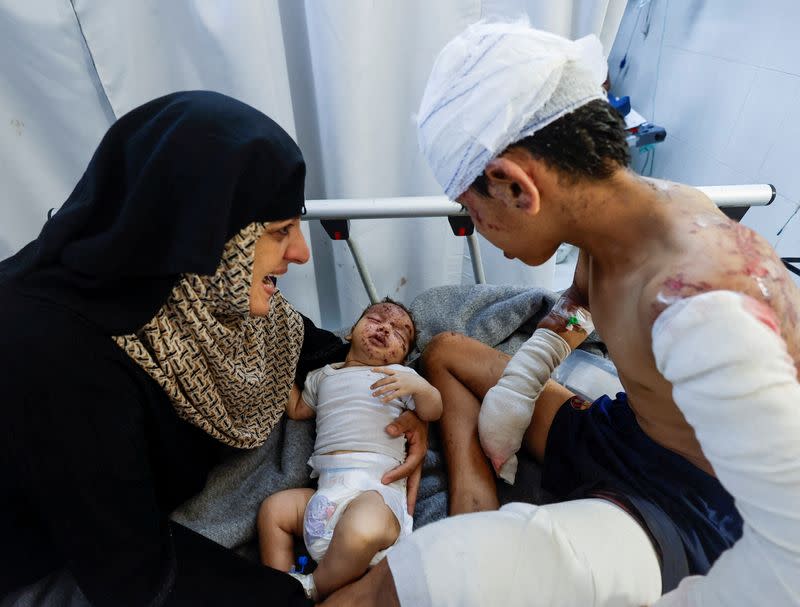 Palestinian child Tareq Qamar, who was injured in an Israeli strike that killed his mother, is carried by his aunt as his brother Mohammed who was wounded along with him rests on a bed, at Nasser hospital, in Khan Younis in the southern Gaza Strip