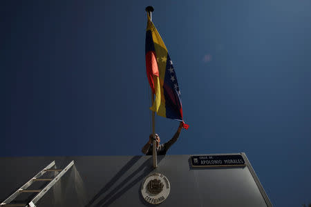 A worker untangles the Venezuelan flag outside the Venezuelan Consulate in Madrid, Spain, May 16, 2018. REUTERS/Susana Vera