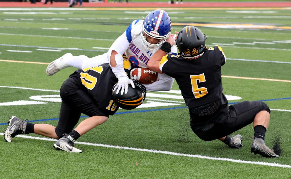 Pearl River's Nicholas Espinal carries the ball as Nanuet's Joseph Mirro and Thomas Ryan defend in their football game at Nanuet High School, Oct. 21, 2023.