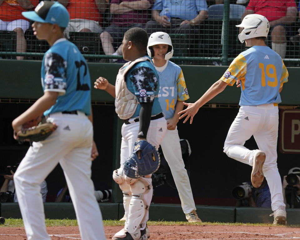 El Segundo, Calif.'s Louis Lappe (19) and celebrate after scoring on a double by Lucas Keldorf off Curacao's Sean Serverie (12) during the first inning of the Little League World Series Championship game in South Williamsport, Pa., Sunday, Aug. 27, 2023. (AP Photo/Gene J. Puskar)