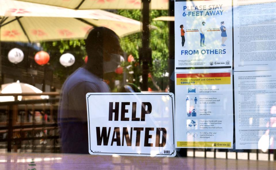 A &quot;Help wanted&quot; sign is posted beside coronavirus safety guidelines in front of a restaurant May 28 in Los Angeles.