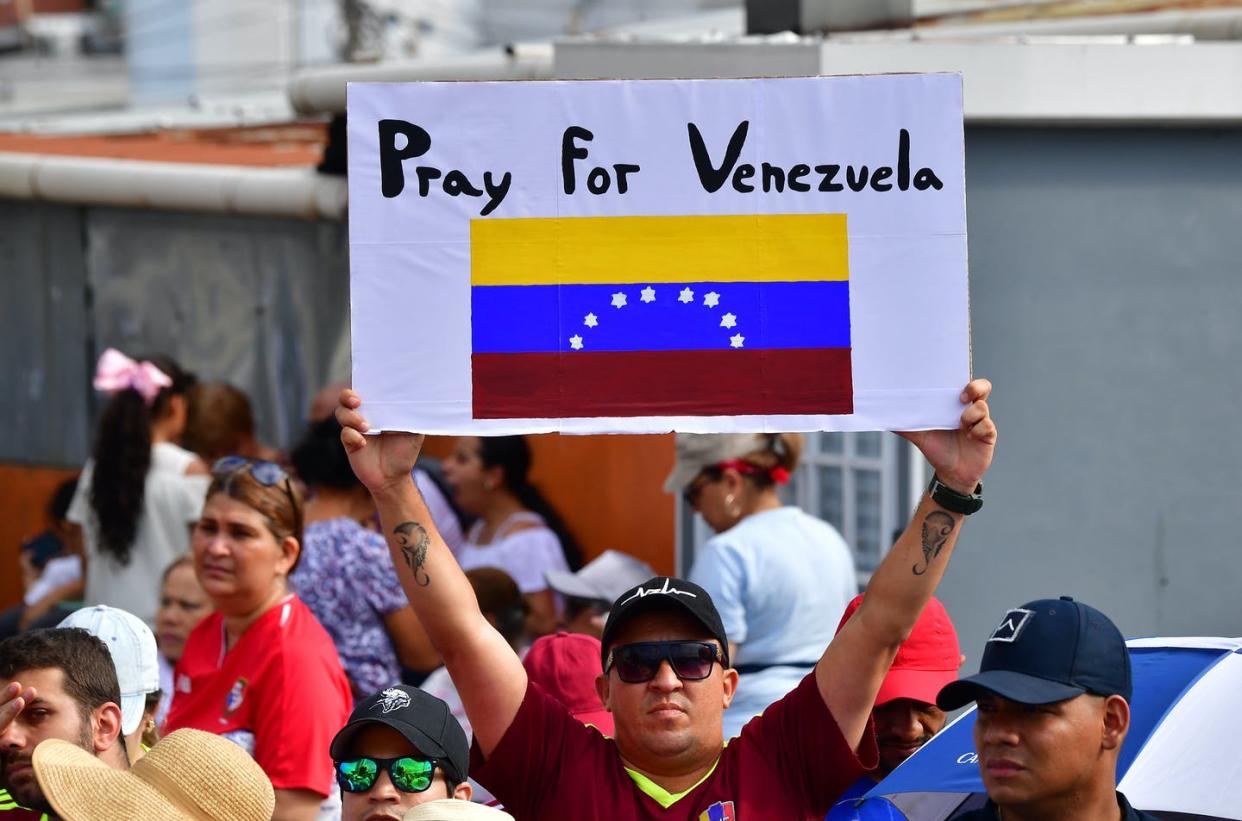 <span class="caption">He may be praying, but so far the Pope has declined to intervene in Venezuela's crisis to aid a unified coronavirus response.</span> <span class="attribution"><a class="link " href="https://www.gettyimages.com/detail/news-photo/venezuelan-faithful-holds-a-sign-as-he-waits-for-the-news-photo/1087321398?adppopup=true" rel="nofollow noopener" target="_blank" data-ylk="slk:LUIS ACOSTA/AFP via Getty Images;elm:context_link;itc:0;sec:content-canvas">LUIS ACOSTA/AFP via Getty Images</a></span>