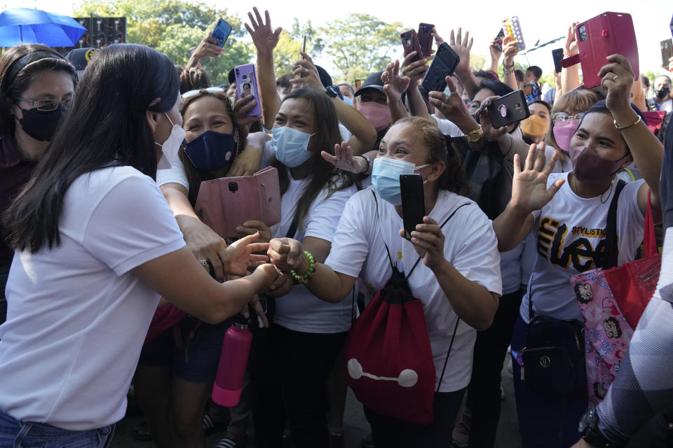 Supporters greet Quezon City Mayor Joy Belmonte, left, as she starts her re-election campaign in Quezon City, Philippines on Friday, March 25, 2022. Candidates for thousands of provincial, town and congressional posts started campaigning across the Philippines Friday under tight police watch due to a history of violent rivalries and to enforce a lingering pandemic ban on handshakes, hugging and tightly packed crowds that are a hallmark of often circus-like campaigns. (AP Photo/Aaron Favila)