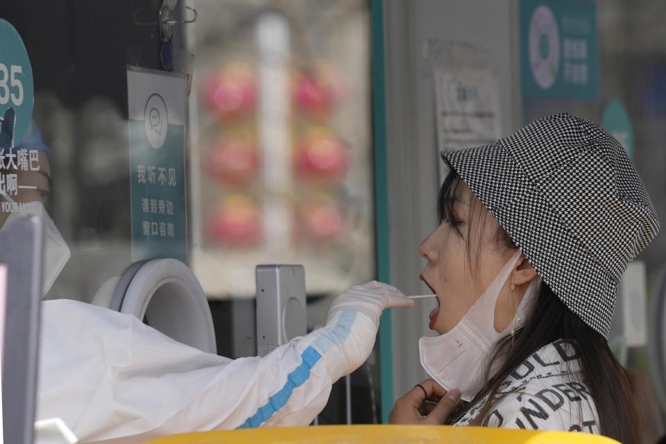 A worker takes a swab sample for a COVID-19 test at a mobile testing site on Tuesday, March 15, 2022, in Beijing. China's new COVID-19 cases Tuesday more than doubled from the previous day as the country faces by far its biggest outbreak since the early days of the pandemic. (AP Photo/Ng Han Guan)