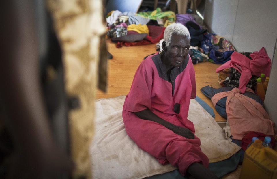 An elderly woman who hid from rebels in an office during the recent fighting, speaks to a South Sudanese government soldier, left, in Bor, Jonglei State, South Sudan Sunday, Jan. 19, 2014. Leaders for warring sides in South Sudan's monthlong internal conflict say they are close to signing a cease-fire and the South Sudanese military spokesman said that army forces had retaken the key city of Bor Saturday, defeating 15,000 rebels. (AP Photo/Mackenzie Knowles-Coursin)