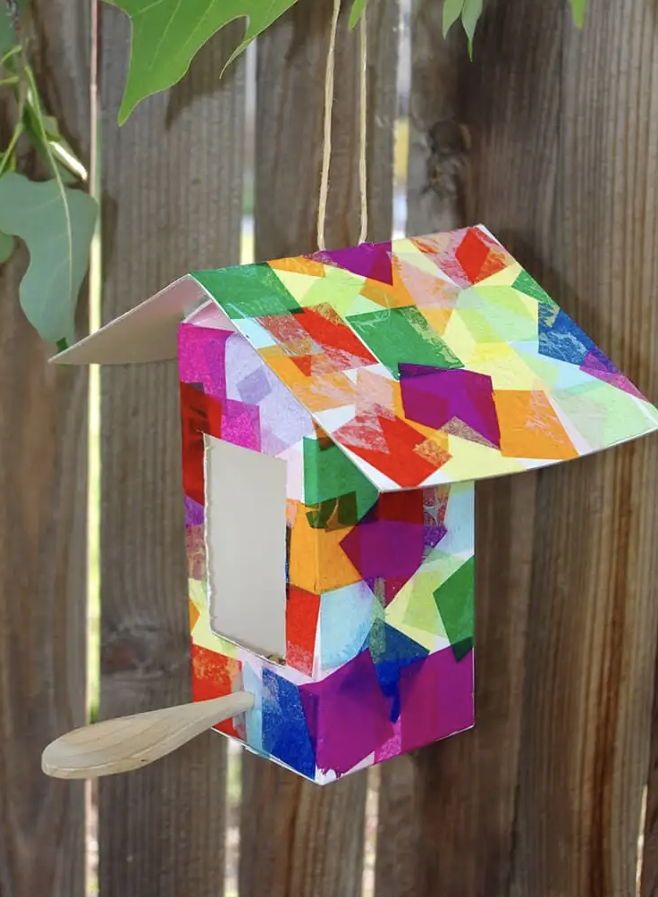 crafts for kids, birdhouse made of a milk carton and tissue paper squares, attached to the fence