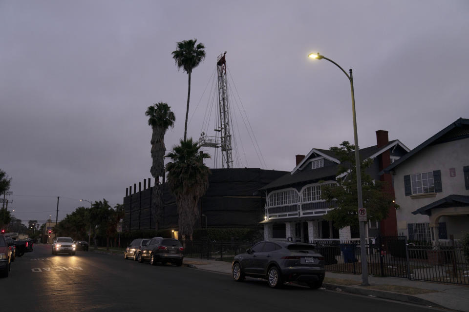 FILE - A vehicle drives past the Jefferson oil drill site located in the residential area in Los Angeles, Wednesday, June 2, 2021. University of Southern California researchers found people living near wells in Jefferson Park reported significantly higher rates of wheezing, eye and nose irritation, sore throat and dizziness than neighbors living farther away. On Wednesday, Jan. 26, 2022, the Los Angeles City Council approved a measure to ban new oil and gas wells and phase out existing ones. (AP Photo/Jae C. Hong, File)