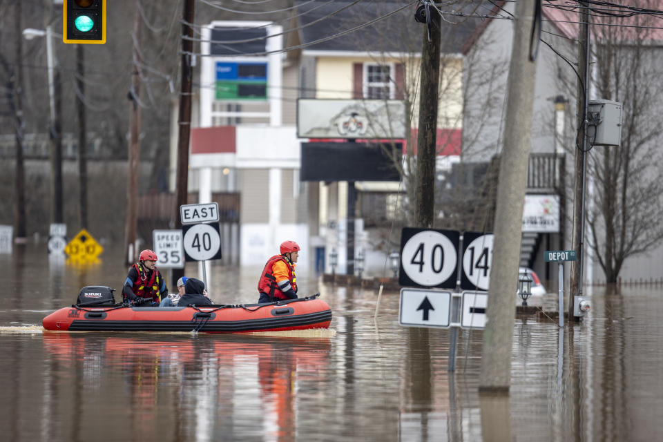 Ricky Keeton, left, of the Oil Springs Fire Department, and Michael Oiler, of the Thelma Fire Department, make their way through floodwaters as they conduct a water rescue following heavy rain in Paintsville, Ky., Monday, March 1, 2021. (Ryan C. Hermens/Lexington Herald-Leader via AP)