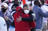 Rutgers head coach Greg Schiano, with a mask, is hugged by an assistant after his team defeated Michigan State in an NCAA college football game, Saturday, Oct. 24, 2020, in East Lansing, Mich. (AP Photo/Carlos Osorio)