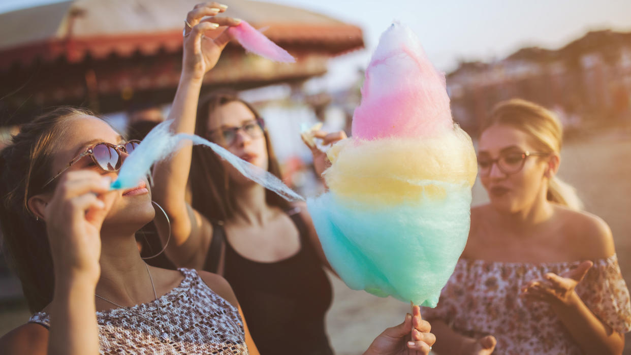 Girls having fun with cotton candy at the county fair in summer.