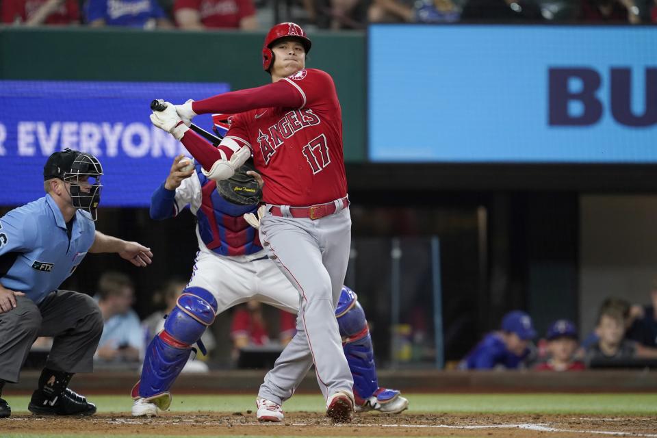 Los Angeles Angels' Shohei Ohtani swings at a pitch in the second inning of a baseball game as Texas Rangers catcher Jose Trevino, rear, throws to third to pick off Juan Lagares in Arlington, Texas, Wednesday, Sept. 29, 2021. Home plate umpire Mike Muchlinski looks on at the play. (AP Photo/Tony Gutierrez)