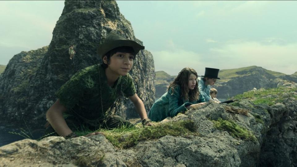 wendy, peter pan, and a person in a top hat peek over a cliff