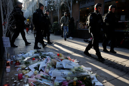 French police walk past flowers and candles that are placed in the Rue des Orfevres street in tribute to the victims of the deadly shooting as they patrol in Strasbourg, France, December 13, 2018. REUTERS/Vincent Kessler