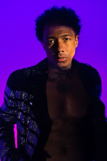 Nick Cannon in a sparkly suit lit in a blue and purple lighting