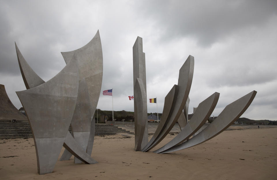 In this photo taken on Thursday, June 4, 2020, a man walks by the US flag and a monument called Les Braves, by sculptor Anilore Banon, at Omaha Beach in Saint-Laurent-sur-Mer, Normandy, France. In sharp contrast to the 75th anniversary of D-Day, this year's 76th will be one of the loneliest remembrances ever, as the coronavirus pandemic is keeping nearly everyone from traveling. (AP Photo/Virginia Mayo)