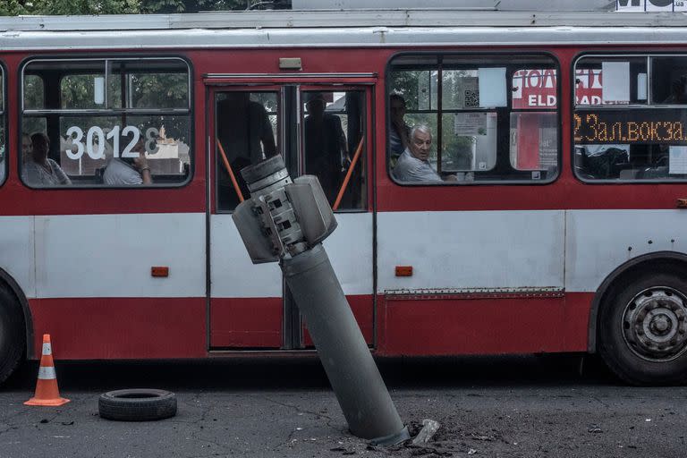 Civiles observan desde un autobús un cohete con bombas de racimo ruso Smerch sin explotar en una de las principales avenidas en Mikolaiv, el 4 de agosto de 2022.