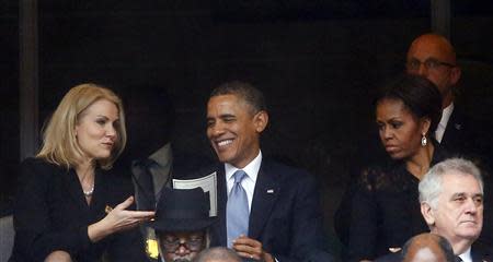 U.S. President Barack Obama (C) speaks with Danish Prime Minister Helle Thorning-Schmidt (L) as his wife, U.S. first lady Michelle Obama looks on during a memorial service for late South African President Nelson Mandela at the FNB soccer stadium in Johannesburg December 10, 2013. Picture taken December 10. REUTERS/Kai Pfaffenbach